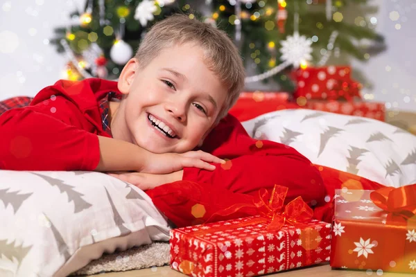 Портрет смішного усміхненого хлопчика Дивлячись на камеру, брехня оточена подарунками . — стокове фото