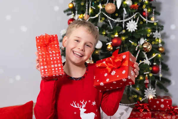Feliz niño sonriente con cajas de regalo de Navidad cerca del árbol de Navidad. — Foto de Stock