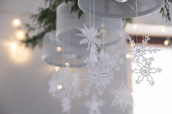 Mooie winter interieur decoratie. Witte gebreide sneeuwvlokken hangen aan een kroonluchter in het kersthuis. — Stockfoto