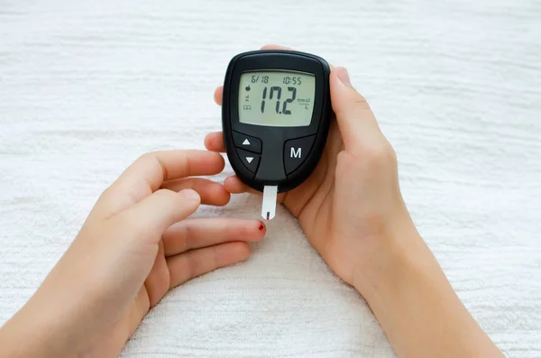 Diabetes test. Child hands checking blood sugar level by Glucose meter.