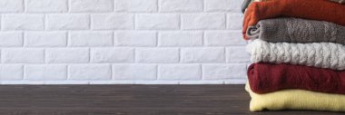 Ahşap masada örülmüş kalın giysiler yığını. Pankart. Sonbahar ve kış arkaplanı.