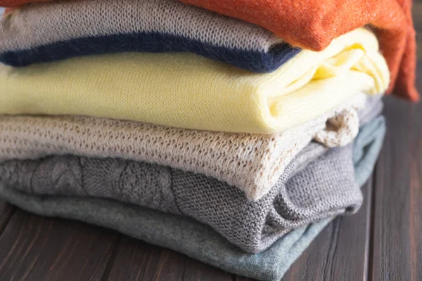 Kahverengi ahşap arka planda sonbahar renklerinde rahat kazaklar..