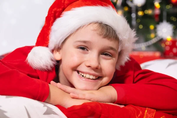 Merry Christmas holidays. Portrait of Funny Smiling Child in Santa Red Hat Looking at Camera.