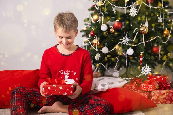 Portrait of Excited Boy in Red Pajamas Holding Christmas Gift Позитивні емоції під час різдвяних свят.. — стокове фото