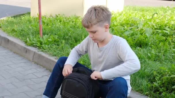 Schoolboy tira garrafa de sua mochila escolar e bebe água. — Vídeo de Stock