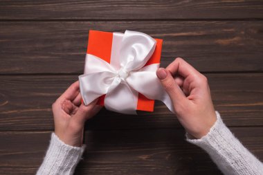 Kadınların elleri Noel hediyesinde beyaz kurdeleyi çözer.