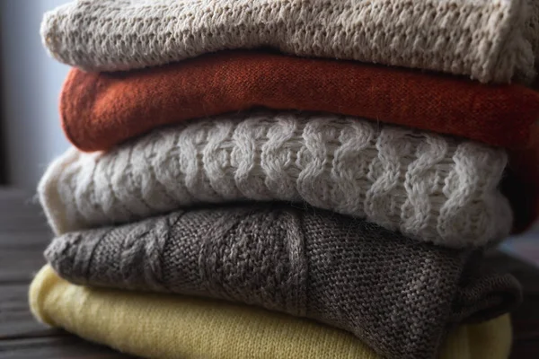 Les pulls chauds tricotés pliés sont empilés. Différents motifs tricotés. Automne ou hiver fond. — Photo
