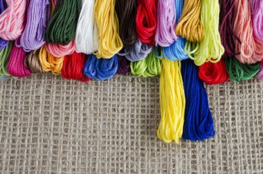 İş parçacığının renkli skeins bir doğal keten arka plan üstünde yalan,