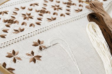 Kahverengi ve bej renk üzerine yağlıboya, ahşap masa üzerinde nakış deseni ile ahşap hoop. Rustik tarzı. Seçici odak.