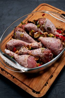 Çiğ tavuk bacağı ve arka planda şeffaf bir tabakta bolca baharat..