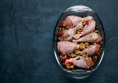 Çiğ tavuk bacağı ve arka planda şeffaf bir tabakta bolca baharat..