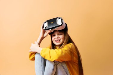 Hevesli küçük kız sanal gerçeklik kulaklık takıyor modern icat cihazı sarıya izole edilmiş.
