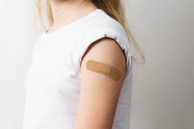 Coronavirus aşısı aşısı sonrası tıbbi yapıştırıcıyla kaplanmış bir kızın omzu.
