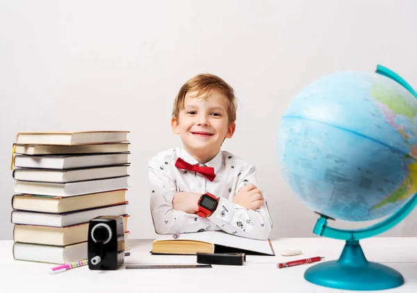 Маленький хлопчик у білій сорочці і червона краватка з великим автомобілем розумний годинник на руці робить домашнє завдання для школи . — стокове фото