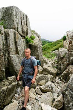 Aktif erkek sırt çantalı dağda yürüyüş yapıyor yaz tatili aktivitelerinin keyfini çıkarıyor.