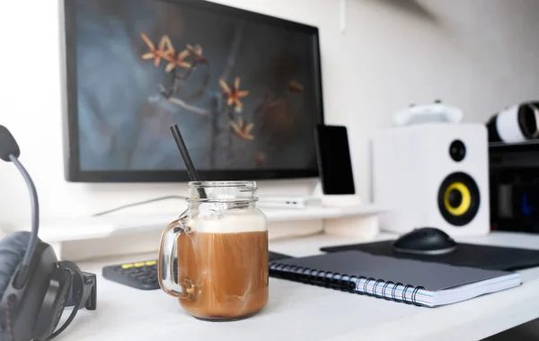 Bilgisayar monitörlü, ses hoparlörlü ve sütlü kahveli modern ofis işyeri — Stok fotoğraf