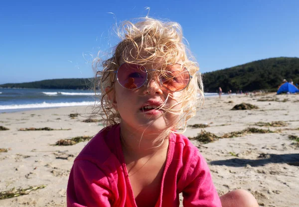 Cara de cerca de la chica divertida con gafas de sol de color rosa posando en la playa disfrutando de vacaciones de verano — Foto de Stock