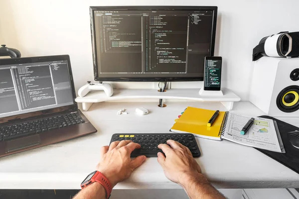男性在现代开发人员工作场所的笔记本电脑上的密切合作，以编写代码. 图库图片