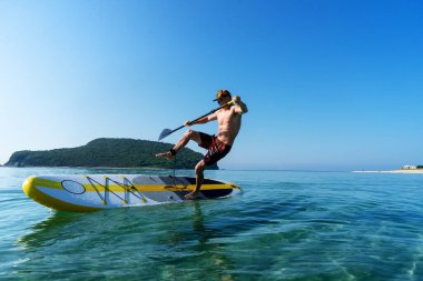 Tanned sportsman falling to sea water practicing supsurfing with paddle extreme sport leisure clipart