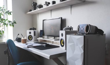 Bilgisayar monitörlü, ses hoparlörlü ve sütlü kahveli modern ofis işyeri