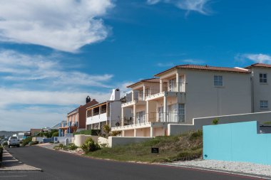 GANSBAAI, Güney Afrika - 12 Nisan 2021: Batı Cape Eyaleti 'nin Gansbaai yakınlarındaki Die Kelders' da sokak sahnesi. Evler ve araçlar görünür.