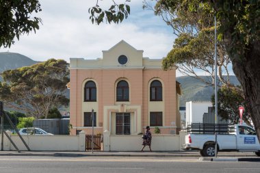 Hermanus, Güney Afrika - 12 Nisan 2021, tarihi Yahudi Sinagogu 'nun bulunduğu bir sokak sahnesi, Hermanus, Batı Cape Eyaleti. Araçlar ve bir kadın görünüyor.