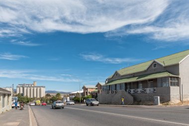 CALEDON, Güney Afrika - 12 Nisan 2021: Batı Cape Eyaleti 'ndeki Caledon' da binalar, insanlar ve araçlarla dolu bir sokak sahnesi. Tahıl ambarları görünür.