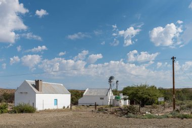 PRINCE ALBERT YOLU, SOUTH AFRICA - 20 Nisan 2021: Batı Cape Eyaleti 'ndeki Prince Albert Yolu yakınlarındaki R407 yolunun yanındaki çiftlik evi. Yel değirmenleri görünür.
