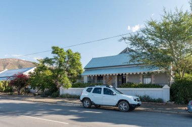 PRINCE ALBERT, GÜNEY AFRİKA - 20 Nisan 2021: Tarihi bir ev ve araçla dolu bir sokak sahnesi, Batı Cape Eyaleti 'nde Prens Albert' te