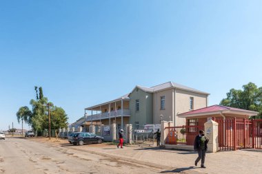 ALIWAL NORTH, Güney Afrika - 23 Nisan 2021: Doğu Cape Eyaleti Aliwal North 'taki Ikhala FET Koleji ile bir sokak sahnesi. İnsanlar ve araçlar görünür.