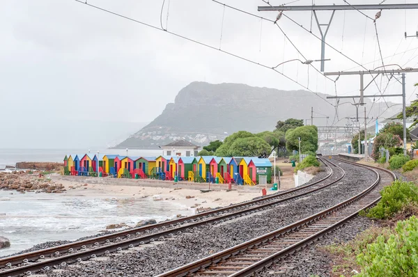 Multi-colored beach huts at St. James with railroad passing by