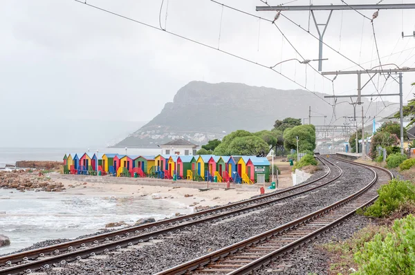 Cabañas de playa multicolores en St. James con ferrocarril pasando por Fotos de stock