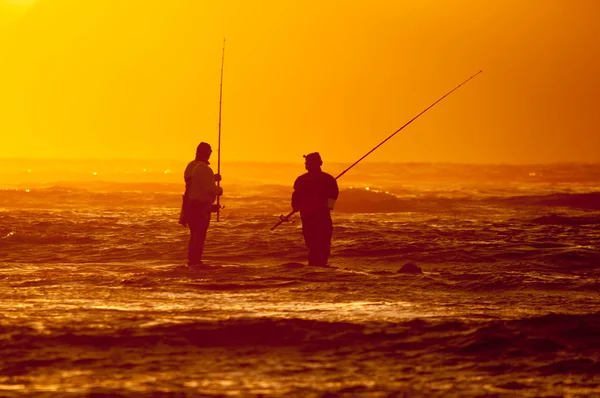 Silhouette de deux pêcheurs contre le coucher du soleil — Photo