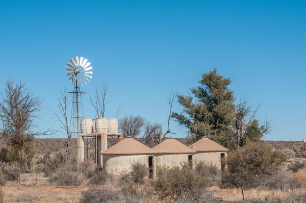 Rondavels junto a una bomba de viento y tanques de almacenamiento de agua — Foto de Stock