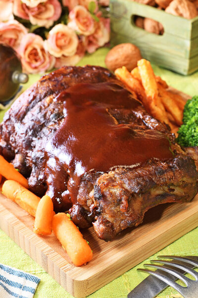 Grilled and smoked pork ribs with barbeque sauce on a wooden board. 