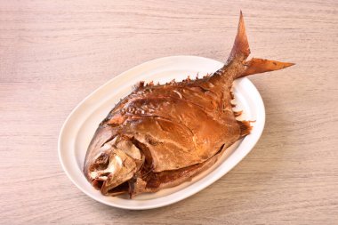 Beyaz tabakta füme altın pomfret. (Çince 'para kazan, şanslı' demek, bir logo ya da marka değil..)  