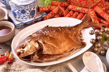 Beyaz tabakta füme altın pomfret. (Çince 'para kazan, şanslı' demek, bir logo ya da marka değil..)  