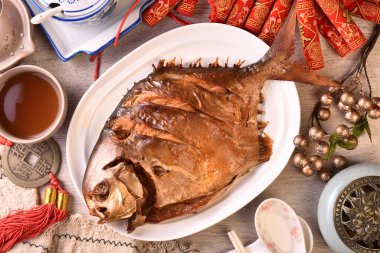 Beyaz tabakta füme altın pomfret. (Çince 'para kazan, şanslı' demek, bir logo ya da marka değil..)  