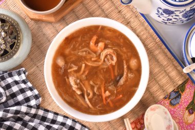 Beyaz kasede deniz tarağı çorbası ile çeşitli deniz ürünleri.