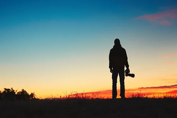 Silhueta de fotógrafo jovem está desfrutando do sol. Fotógrafo ao nascer do sol — Fotografia de Stock