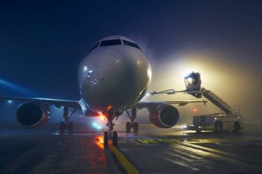 Winter frosty night at airport. Deicing of airplane before flight.  clipart