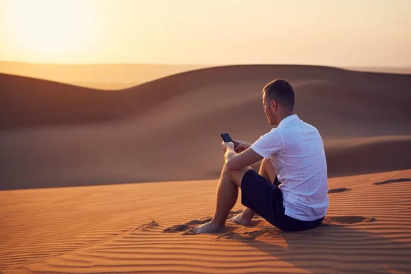 Sozinho Deserto Jovem Sentado Duna Areia Usando Telefone Pôr Sol — Fotografia de Stock