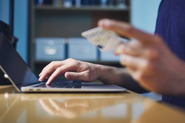 Çevrimiçi shooping sırasında kişinin yakın çekim elleri. Kredi kartı tutan ve dizüstü bilgisayar kullanan genç adam..