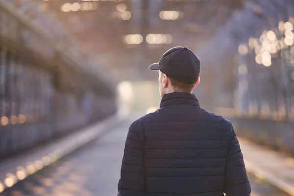 一个孤独的人在日出时走在桥上 头戴帽子的青年男子的后视镜 — 图库照片
