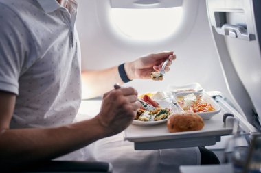 Uçak yemeği yiyen yolcu. Orta büyüklükteki taşımacılık uçuşunda business class menüsü.
