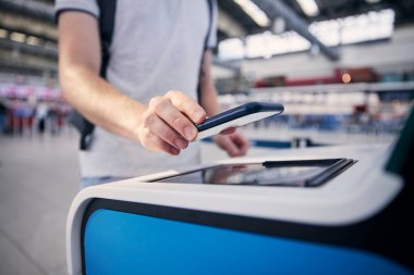 Öz servis kayıt makinesini kullanırken adamın eli. Havaalanı terminalindeki akıllı telefondan yolcu tarama bileti
