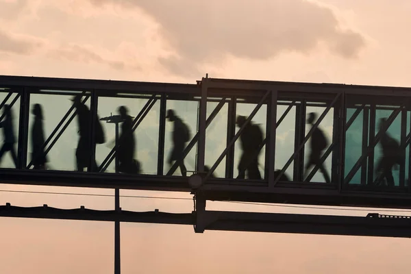 忙しい空港を歩いている人々のシルエット 搭乗橋の中を歩く乗客 — ストック写真