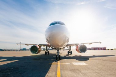 Güneşli bir günde havaalanı pistine doğru giden uçağın ön görüntüsü. Ticari havacılık, hava taşımacılığı, ulaşım, hareket ve havaalanı operasyonları kavramı.