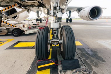 Uçuş öncesi hazırlık ve yükleme sırasında havaalanındaki ticari uçağın iniş takımlarının yakın görüntüsü. Havacılık, yer işleme ve hava taşımacılığı kavramı.