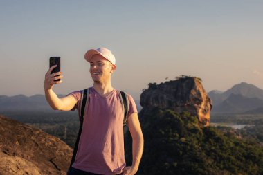 Sırt çantalı turist, arka planda Sigirya Kayası ile Pidurangala Kayası 'nda selfie çekiyor. Sri Lanka 'da seyahat macerası ve keşif